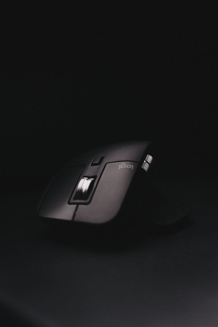 Close-up of a black computer mouse with illuminated scroll wheel on a dark background.